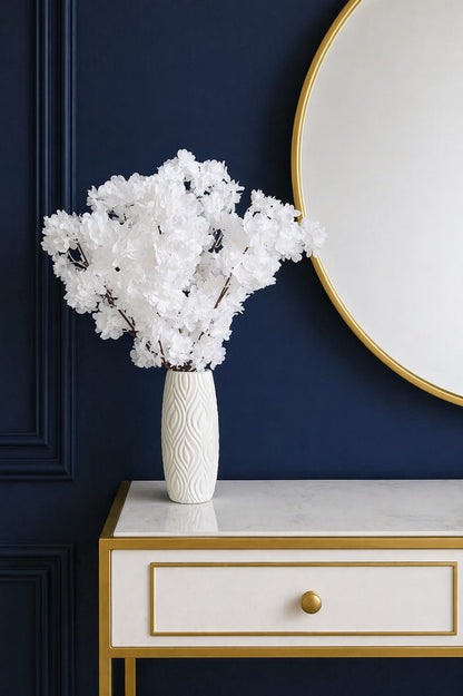 Elegant artificial flowers in a textured white plastic vase